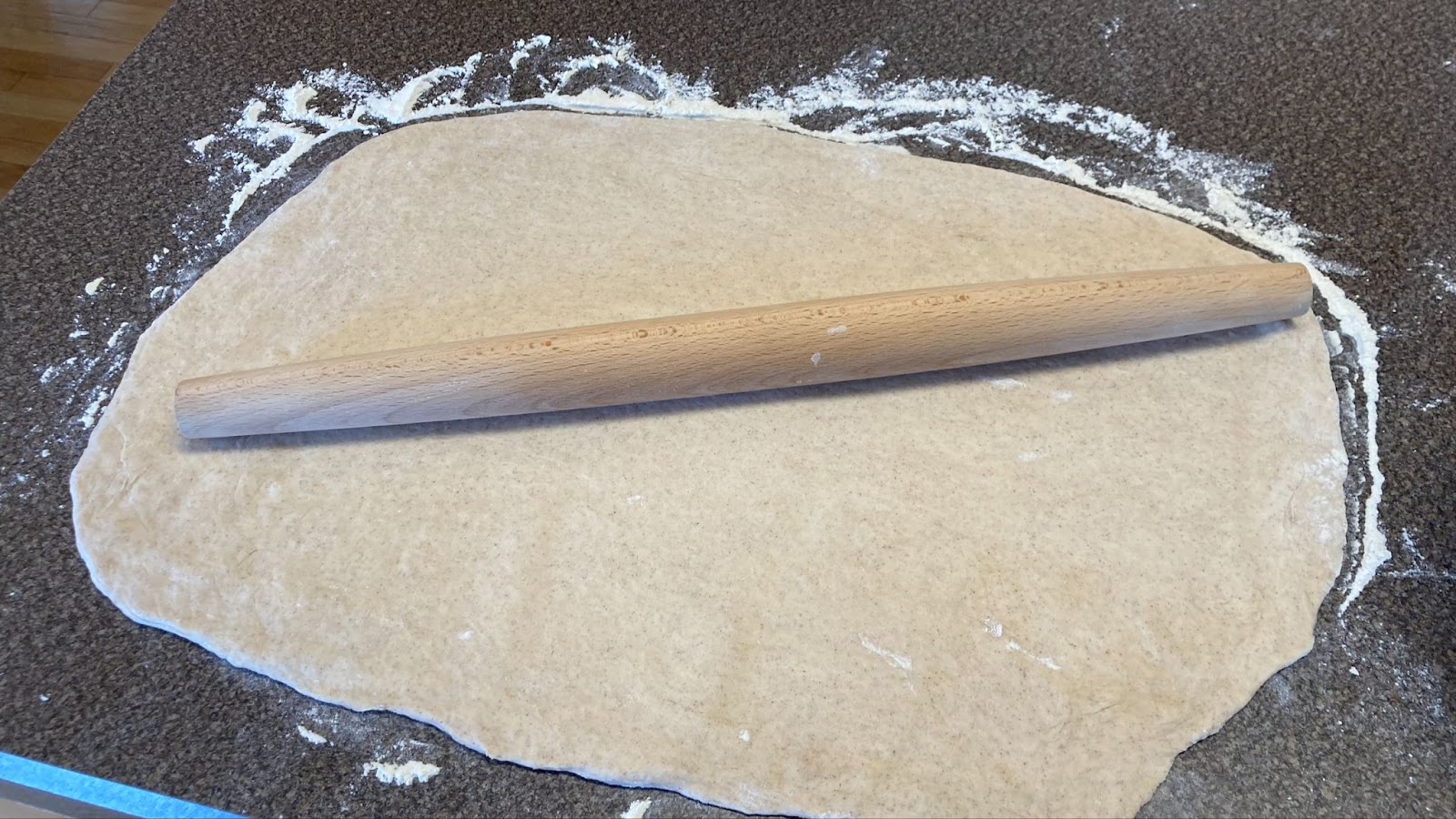 A rolling pin on top of a section of dough getting ready to create cinnamon rolls on the grill