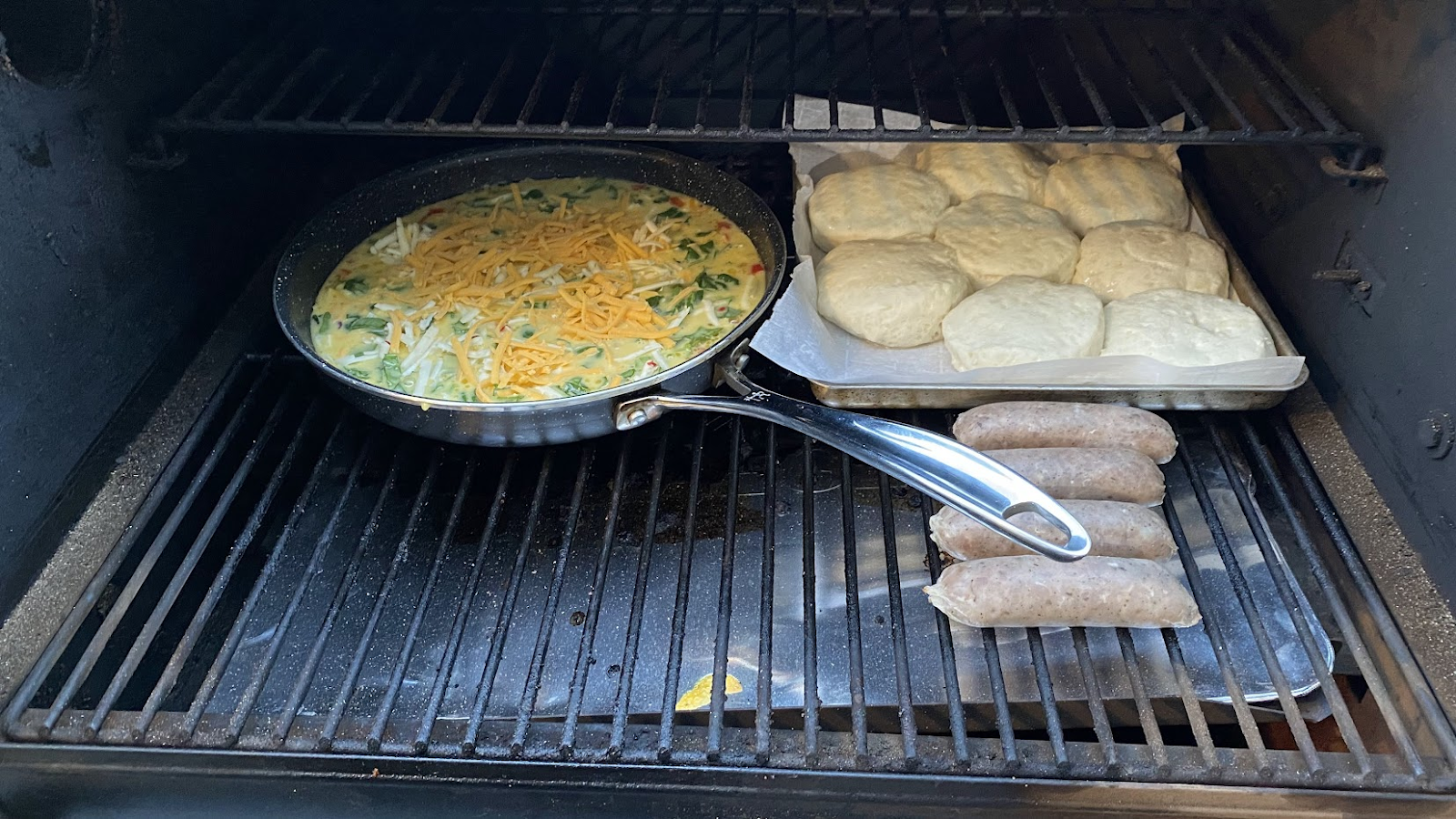 A pan with eggs, biscuits and sausages on the grill