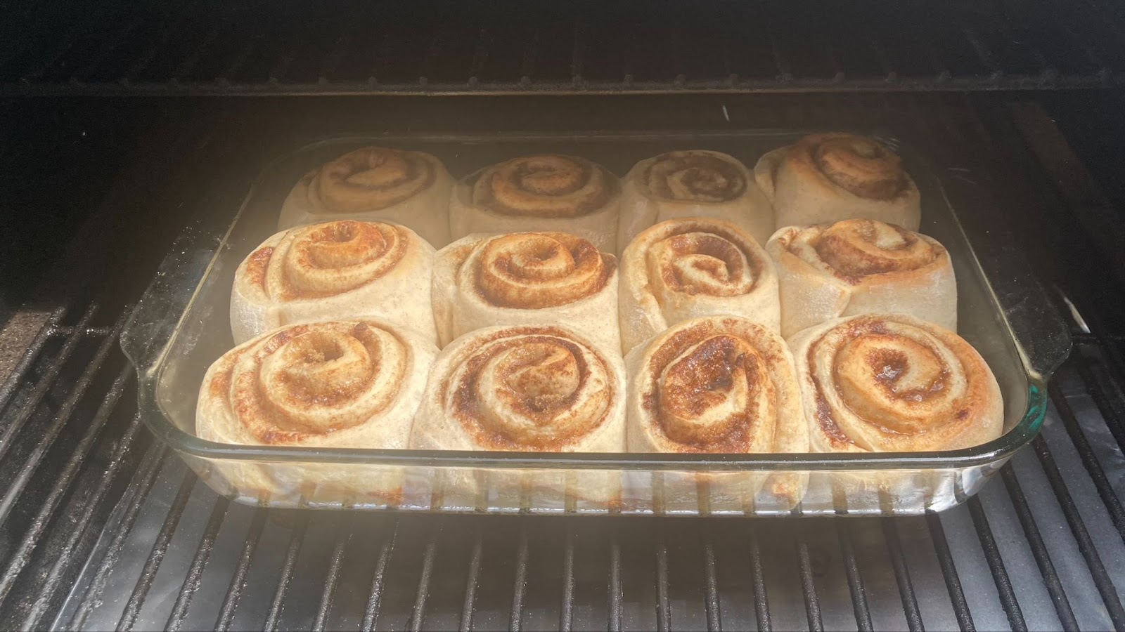 Cinnamon rolls in a glass dish on a grill grate