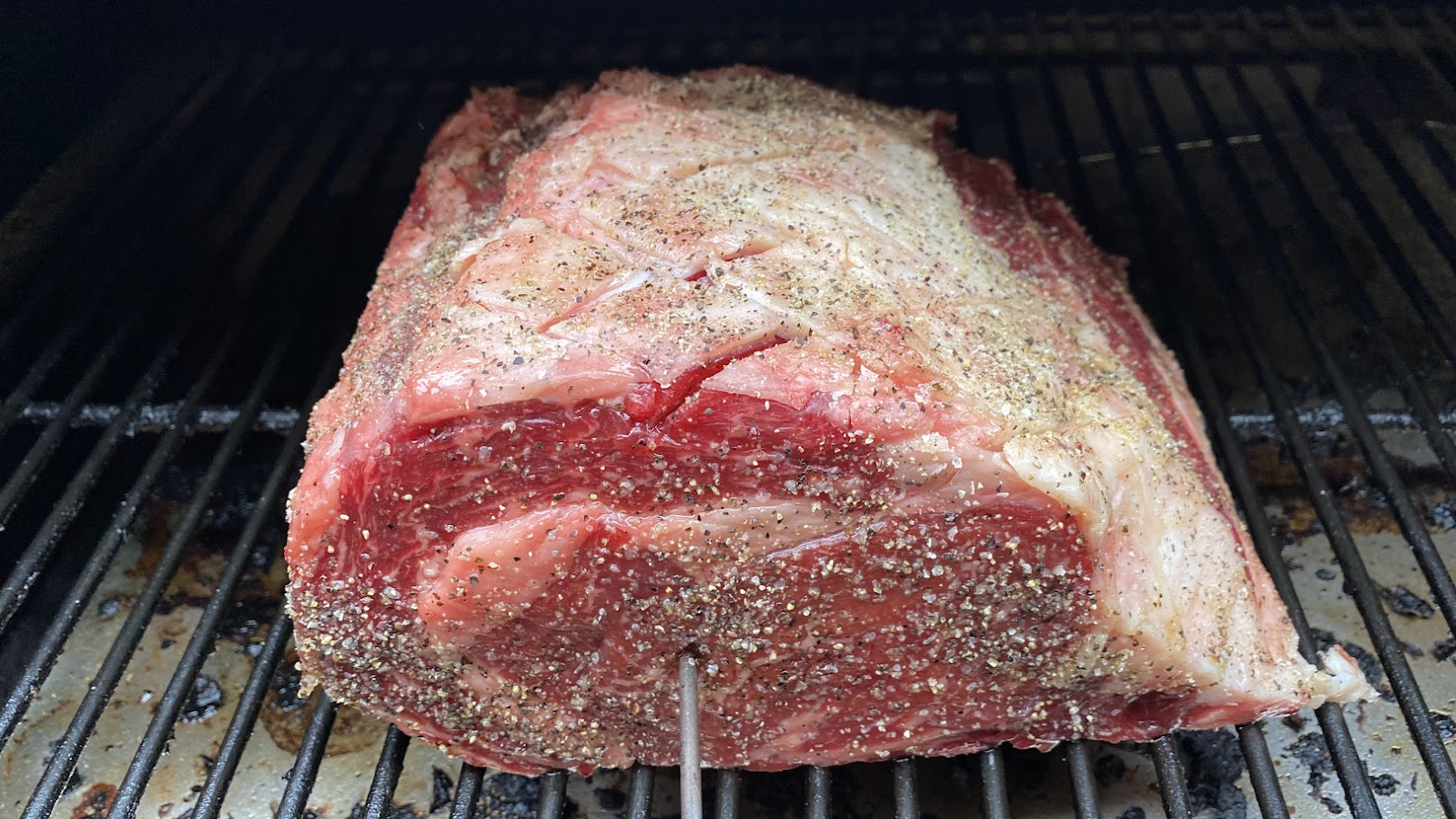 Rare Prime Rib on a grill grate with a temperature probe in the center - Grillers Gold Blog