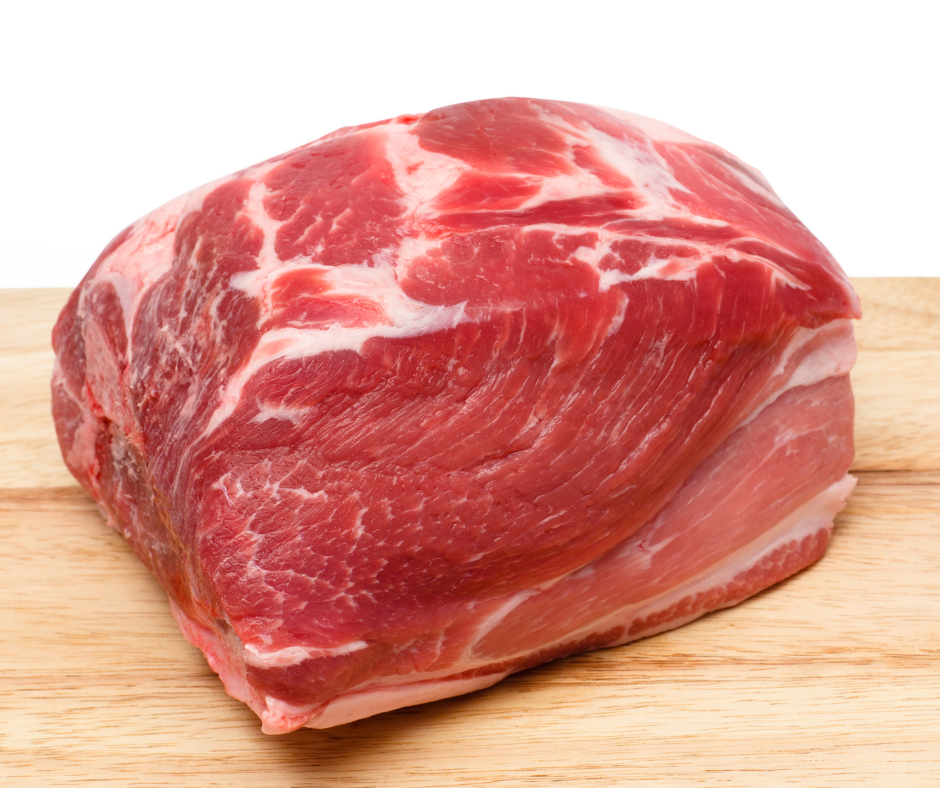 Raw pork shoulder to use for pulled pork on an oak board with a white background