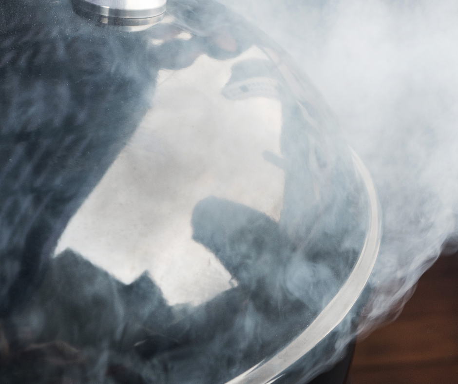 top of a black smoker with smoke billowing out